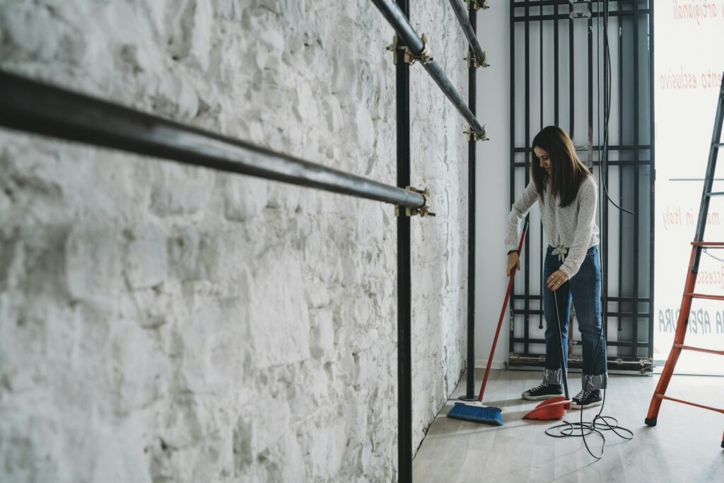 Young woman diligently sweeping the floor at a construction site.